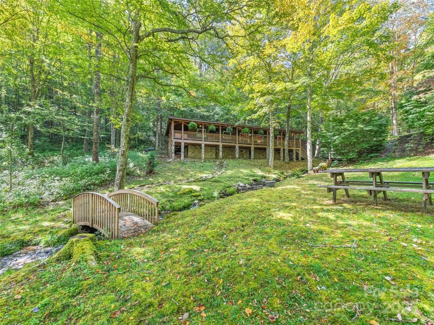 Escape to this private, gated creekside log cabin bordering Blue Ridge Parkway land—an ideal second home or vacation rental. Enjoy the soothing sounds of a bold, trout-stocked stream just steps from your door, with elk and other wildlife roaming freely through the area. Inside, you'll find a kitchen with stainless steel appliances and dual fireplaces—one in the cozy living room and one in the peaceful primary suite Relax year-round on 621 sq. ft. of covered porches, soak in the hot tub overlooking the creek, or gather around the outdoor fire pit. Includes a 23’x16’ workshop/storage for ATVs, a high weight capacity bridge for easy access, and sits at nearly 5,000 ft elevation for cool summer temps and unmatched serenity.