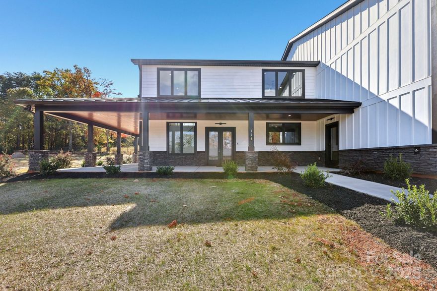 Welcome to Honeyman Estates, an exclusive gated enclave featuring just five luxury barndominiums, a rare opportunity to own one of the most innovative and desirable styles of homes in today’s market. More than just a residence, this property represents a new way of living: blending modern luxury with true practicality, designed for those whose lifestyle is as expansive as their vision. The garage is a masterpiece of its own, designed for more than just storage. With climate-controlled comfort, soaring 16 to 18-foot ceiling heights, epoxy-coated floors, and a powerful 400-amp service panel, this space is fully prepared to house your car collection, provide room for RVs and boats or even your very own indoor pickleball court! Spray foam insulation ensures year-round efficiency, while the impressive volume of the space allows for nearly limitless possibilities. This property offers not only the space but also the freedom to fully embrace your passions. From family living to hobby space, it redefines what home can mean. Step inside to find a stunning great room crowned by soaring vaulted ceilings that draw the eye upward and create an immediate sense of openness and grandeur. Vertical modern cable railing adds a sleek architectural touch, blending contemporary design with the rustic elegance of the barndominium aesthetic. The chef’s kitchen is a true centerpiece, featuring 42” shaker cabinets, quartz countertops, floating shelves, and premium appliances, crafted for both everyday meals and grand entertaining. Luxury vinyl plank flooring flows seamlessly throughout the home, leading to a striking 60” linear fireplace that anchors the living space with warmth and modern sophistication. Outside, the home’s timeless board-and-batten fiber cement siding pairs perfectly with architectural roofing, accented by standing seam metal for the covered porches, to create an aesthetic that is both classic and forward-thinking. Every detail has been considered, from the materials to the craftsmanship, resulting in a property that delivers enduring value and style. This barndominium is not just a home, it is a statement. A practical yet luxurious way of life that merges passion, functionality, and elegance under one roof. Honeyman Estates offers something incredibly rare: exclusivity, sophistication, and space to live life without compromise.