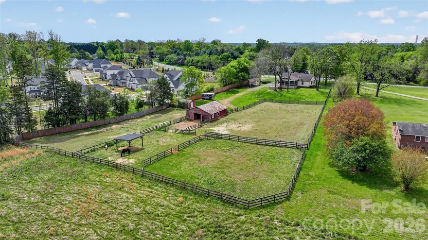 Rare opportunity to own 2 acres in Huntersville, offering a truly unique property that is increasingly hard to find this close to town with the added benefit of no city taxes or HOA fees. The land includes fenced areas, separate paddock spaces, and a five-stall barn with tack room, water and electricity, making it well suited for a small hobby setup for a couple of horses. This property is ideal for anyone needing space and versatility, it's a great fit for a carpenter, car enthusiast, or anyone looking for room to build out a larger garage, workshop, or additional structures. Two separate storage sheds w/lighting add even more functionality, and a privacy fence along one side adds separation and enhances the overall privacy. The massive16x30 covered screened-in porch is a standout, overlooking the back yard and pastures along with a 226 sq. ft open back deck ideal for grilling and entertaining. It offers a peaceful setting where you can relax and enjoy the open space and surroundings. The beautiful redwood cedar ranch home itself offers approximately 1478 square feet and is very well maintained, featuring updated bathrooms, elegant quartz countertops in the kitchen with a large single bowl farmhouse sink overlooking the yard and pastures. It comes fully equipped with stainless steel appliances and a refrigerator that conveys with the sale. The open concept layout flows from the dining area into the living space anchored by a large stone wood-burning fireplace, and high-quality Pergo plank flooring, The Well holding tank is enclosed in shed area and there was a new HVAC-Heat Pump installed in 2023. All of this in a prime Huntersville location, close to shopping, dining and just 20 minutes from Charlotte. Properties like this rarely come available in Huntersville with this much usable land and flexibility.