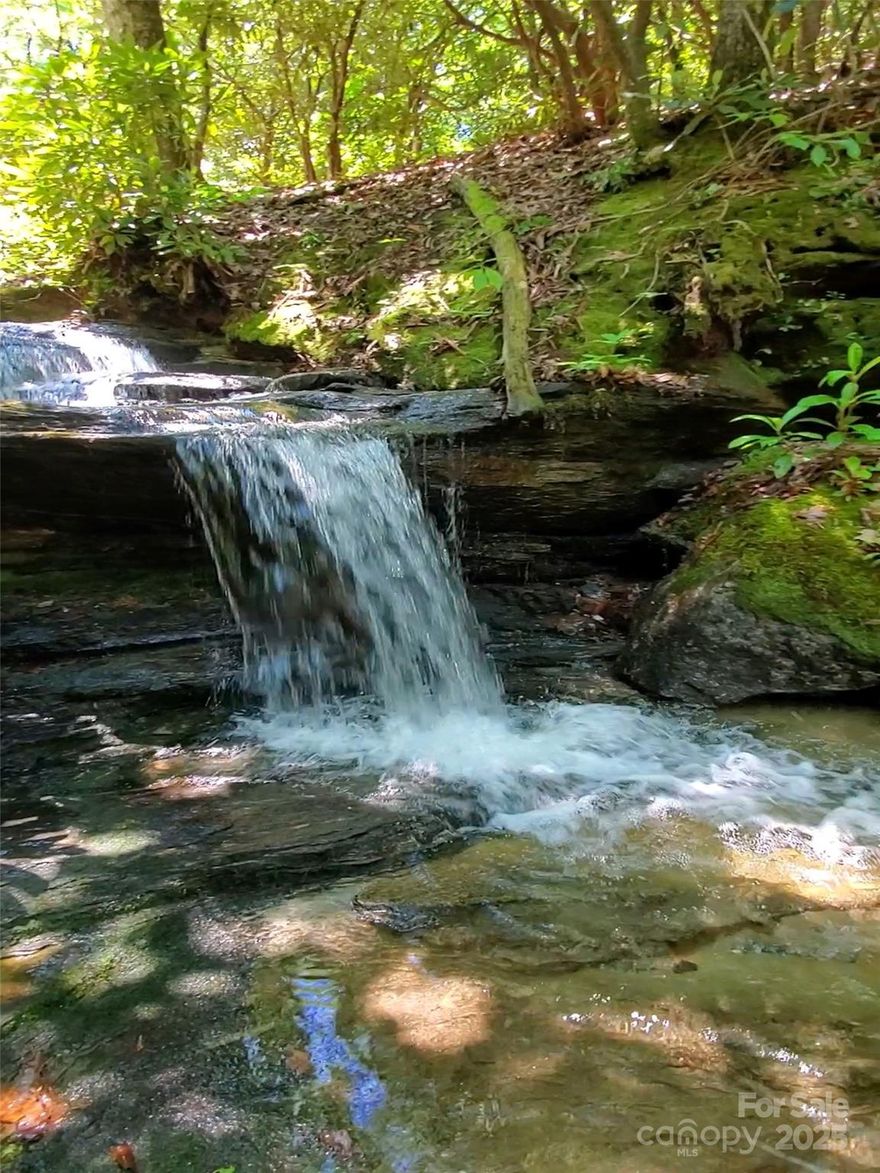 Discover your private mountain retreat at 299 McIntosh Lane in beautiful Lake Toxaway, NC. This 5.11-acre property offers a rare blend of natural beauty and thoughtful improvements. A small, clear stream gently winds through the land, adding a peaceful ambiance with the sound of falling water from your very own waterfall. Cleared areas are ready for your enjoyment, featuring a cozy tiny home, a screened-in pavilion perfect for outdoor dining or relaxing, and multiple storage sheds for your gear and tools. Additional highlights include a composting outhouse, fire pit area for gathering under the stars, and plenty of space for gardening, additional building, or simply soaking in the mountain serenity. Whether you're looking for a weekend getaway, a simple lifestyle retreat, or a basecamp for exploring nearby waterfalls, trails, and lakes, this property is full of potential. Come experience the quiet charm of Lake Toxaway with no HOA restrictions—your mountain escape awaits.