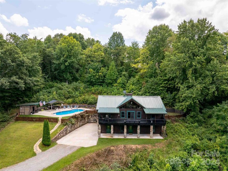 Don't miss this spectacular D-log home in the desirable Bethel area of Haywood County, just minutes from
the Blue Ridge Parkway and centrally-located between downtown Waynesville and Canton. Nestled on a
private, unrestricted 4.38-acre lot, this 3-bed/3-bath home boasts over 2,560 sq ft. of finished area. The
spacious kitchen and open floorplan compliment the main-level primary suite and stunning stonework,
including upper & lower floor-to-ceiling fireplaces and exterior stone columns. The great room features
vaulted ceilings and expansive views, connecting to an open home office area. The basement level offers a
large family room, additional bedroom, 2 guest bathrooms, and an oversized 1-car garage. Outside, enjoy
the beautiful relaxing pool area and pool house with a powder room and full bar area inside -- perfect for
entertaining. This stunning mountain retreat is a must-see!