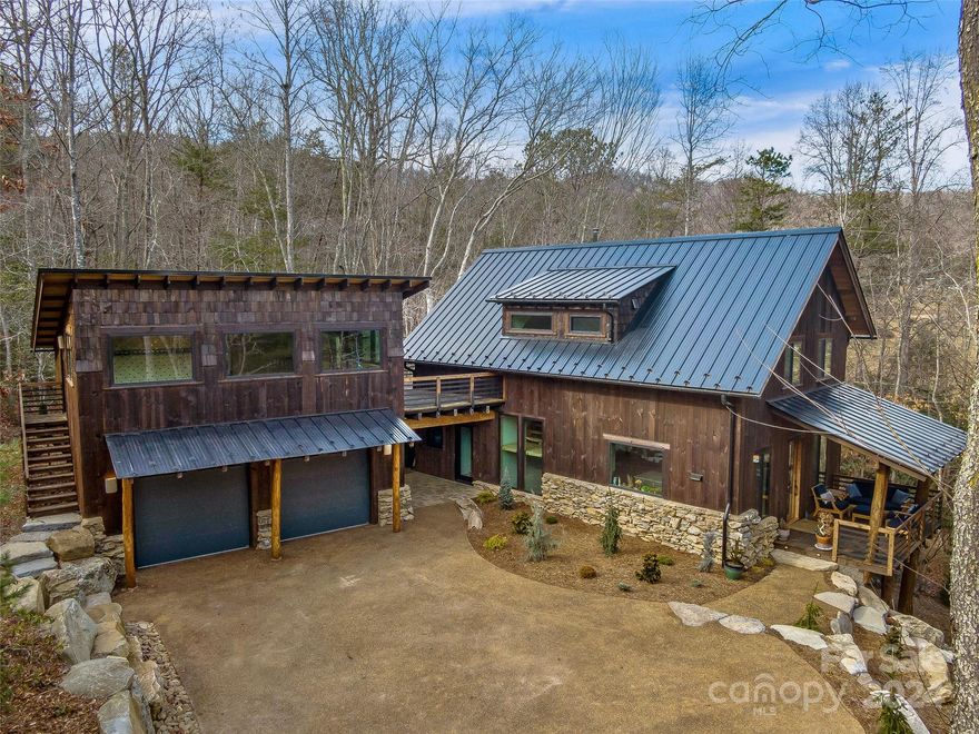 This rustic yet modern retreat in Bent Creek Preserve offers a treehouse-like experience with expansive windows framing nature views. Nestled in an outdoor lover's paradise with National Forest access through a common trail easement to the Bent Creek Trail System and just 5 minutes from the NC Arboretum, this home seamlessly blends indoor and outdoor living. The kitchen features high-end appliances, including a Wolf hood, induction range and a SubZero fridge, with quartz counters and a spacious island connecting to the great room. The finished basement boasts radiant floor heating, a sauna, and a recreation room. The primary suite showcases tall ceilings and a generous walk-in closet, and connects to a home gym located in the flex space above the garage. Additional highlights include exposed beam ceilings, a second-level deck wired for a hot tub, and a detached two-car garage with an EV charger. All of this is within a convenient 15-minute drive to downtown or South Asheville.