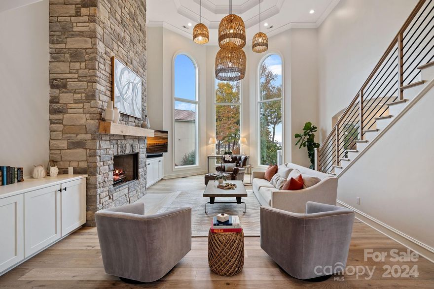 This stunning waterfront gem in The Peninsula offers not just a home, but a lifestyle! Long range water views from most rooms throughout this newly refreshed residence that has been carefully curated to meet the highest standards of modern luxury living. The glass steel front doors lead to the heart of the home; the great room, where soaring ceilings and expansive windows create a bright and inviting atmosphere. With a focus on open concept living, the home flows effortlessly from one beautifully appointed room to the next. The gourmet kitchen is a chef's dream, equipped with WOLF appliances, custom cabinetry, and spacious island overlooking the lake. Enjoy dual primary suites on both the main and upper levels. Entertain guests in the lower level featuring a wet bar, living room w/cozy fireplace, full gym, en-suite bedroom, and oversized storage room. Meander down the stone pathway and through the large, grassy fenced-in yard to enjoy evening lakeside sunsets by the dock and boardwalk.