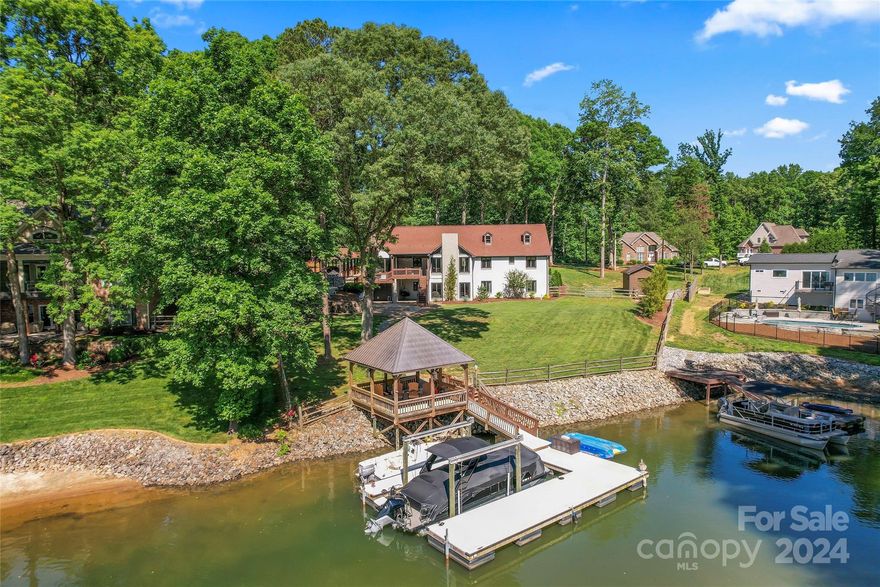 30’ GRANDFATHERED IN SET BACK!! Sitting 0.8+ acres on Lake Norman, enjoy expansive nightly sunset views. With over 4100 sqft, this 5BR/5.5BA + bonus room home has both the bedrooms and living space one desires. Every bedroom has its' own en suite bath!! Home has been connected to CITY SEWER! NO HOA! Hardwoods WHOLE HOME. Living room feat. cathedral ceilings w/ exposed wooden beams & beautiful natural light. Chefs kitchen w/ stainless appliances & granite countertops. Additional 2nd living quarters in basement w/ 2nd kitchen - granite, stainless steel appliances & bar area. Additional bonus room downstairs w/ MASSIVE custom closet. Backyard has endless possibilities  - POOL PERMIT IN HAND. Roof 2019; HVAC upstairs 2023. Enjoy beautiful views off private back deck or on the water w/ covered gazebo off the shore. Plantation shutters. Epoxy garage floors. Close in proximity to all Denver offers including new restaurants, shopping, and local conveniences.