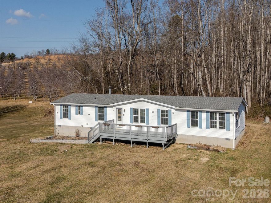 Home offers a spacious living area and a split bedroom plan. Situated on a .71-acre level cleared lot. The open floor plan offers three bedrooms supported by a 3-bedroom septic system, and 2 full baths.  One bath in the Primary Bedroom and the other as the guest/hall bath.  Additional flex space ideal for an office, den or hobby room. A cozy woodburning fireplace enhances the den, while the welcoming living room and kitchen island create flow for everyday living and entertaining. The primary suite serves as a private retreat featuring a large walk-in closet, a primary bath with a relaxing garden tub. Includes the washer and dryer, refrigerator, Oven/Range and Dishwasher. Convenient to groceries, shopping and schools. Just east of Hendersonville. Note: Roof and HVAC updated in 2022. A must-see home offering an open spacious floor plan, flexibility in the use of the 2000+ sf one-level home, and a large front deck overlooking the spacious flat/level front yard.