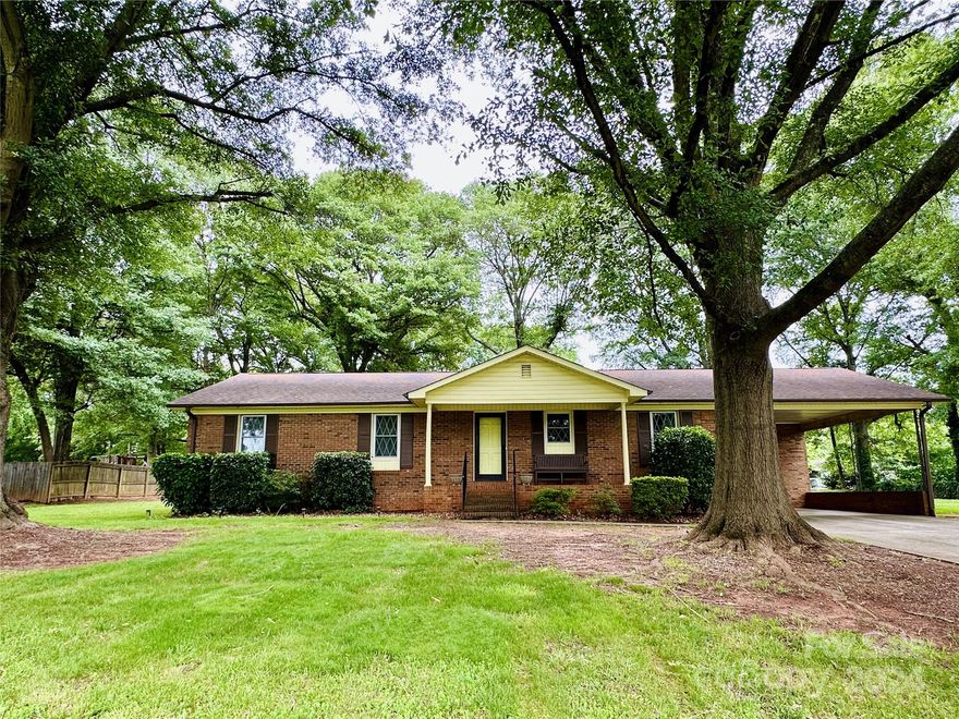 Fabulous Ranch on large level lot in Belmont! No city taxes! Great curb appeal with large covered front porch & stately trees! Kitchen with white cabinets, granite countertops, and eat in breakfast area. Large laundry room also has access to the backyard making it perfect for a mudroom!  Home has been updated with LVP flooring & new windows. Great room with raised hearth brick fireplace. Screen porch, and large patio, perfect for entertaining in your very private backyard! Wired workshop! Primary suite with attached full bath.