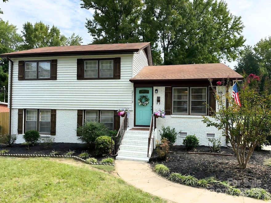 100% financing available for qualifying buyers! This mid century home has kept the charm of its history but added more functionality. Exterior freshly painted in Sherwin Williams Greek Villa white w/new custom shutters. The original hardwoods on the main & upper levels were sanded & refinished beautifully. LVT was added to the kitchen & primary bath. LVP was added to the primary bedroom and lower-level family room. Kitchen boasts new shaker cabinets w/quartz counters, new stainless appliances & an open flow between kitchen and formal living room. Kitchen is staged with a lovely banquette that demonstrates you can seat 6 easily in this cozy corner.  Access to the parking is located off the kitchen with an awning for cover over the side porch. Upper level has three bedrooms, one with two closets, & an updated full bath to be shared by upper bedrooms. One bedroom on the upper level is staged as an ideal office. Lots of closets & storage. Lower level boasts a primary with built ins for closets, including abundant drawers. Primary bath has lovely upgrades including glass shower door. Off the primary you will be delighted with new sliders that lead to a large, screened porch with seating for enjoying the deep, maturely shaded rear yard, & a dining space for outdoor meals. Two doors off the screened porch let you access the covered parking spaces or step off the rear and walk around to a private courtyard staged with a firepit just off the family room. The family room area has space for gaming, a nice television viewing area, and a custom drop zone. The laundry closet is located within the family room space. This could also serve as an excellent home office for those who telecommute! An exit to the side yard with a private courtyard is covered by an awning. The lot is almost 1/2 acre. The rear yard has a storage building that is sold as is to house your lawn and garden items. The former owner added a chain link fence to divide the lot behind the shed for a garden. The lot goes back to the privacy fence of the neighbor, well beyond the initial fence. This home was loved by the same family from 1965 until 2025 when this seller bought it because he saw how lovely it could be, once again. Come and view this historical home, less than 1/2 mile from the Plaza Midwood corridor and steps away from the public transit system that stops on this road. FHA eligible as it has been 90 days since this deed recorded, making it super affordable to finance.  No HOA.