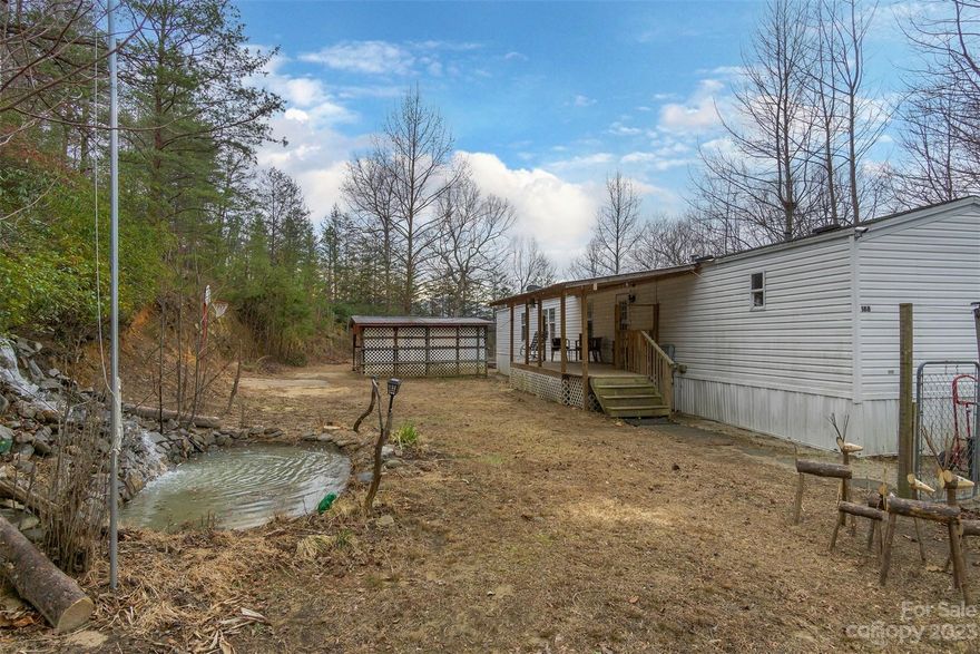This split bedroom home is located on two fenced acres just eight minutes from downtown Old Fort. The large front porch looks over a lovingly tended front yard with a beautiful waterfall into a little pond that is begging for coy fish. Just wait until spring when the plants come out. Red buds, a Japanese Maple, elephant ears, large purple Iris plants and Rose of Sharon are just a few in the front yard. The large vegetable garden also has grapes, blue berries and a peach tree. This is a great spot to hunker down while you work on a project. Two large outbuildings, one with a toilet and shower, would make a great space for a workshop or art studio. Just beyond the main home is a great building spot with potential views over the Crooked Creek Valley. The property is also accessible from McGinnis Road on the downhill side.