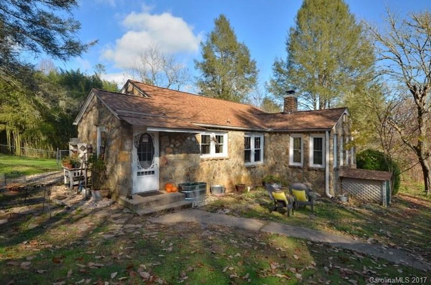 Charming 1940's era stone cottage on nearly two acres a short distance from downtown Brevard largely refreshed in 2006. Country charm  plus modern conveniences such as large double garage with studio/workshop, newer roof, newer well pump, vinyl-tilt windows, new kitchen laminate floors, and hdwood floors. Small creek on property.  Plenty of additional parking. Fenced acreage for pets, chickens, playset. Gardener's delight. Only 2 miles  to Bracken Mtn Preserve trails and Brevard Music Center.