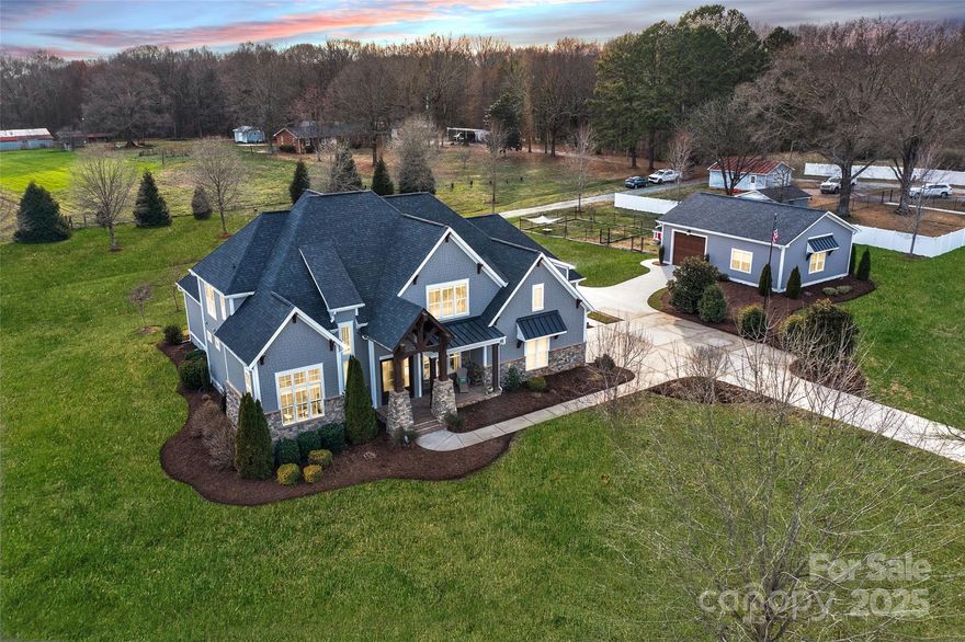 Beautifully crafted, designed home features an open floor plan w/imposing 2-story foyer, executive office, & spacious great room w/fireplace & coffered ceiling. The gourmet kitchen boasts a quartz island, custom cabinetry, top-tier appliances, & hidden walk-in pantry/scullery/laundry suite w/2nd dishwasher. A curved wet bar w/beverage cooler & built-in buffet enhances the entertainment appeal. The luxurious primary bathroom offers a spa-like retreat w/oversized walk-in shower, freestanding soaking tub, dual vanities w/quartz tops, and large walk-in closet w/custom built-ins. Indoor/outdoor living shines w/an all-seasons room, outdoor kitchen, & large patio w/motorized awning. The 3.86 acres provides ample space for animals. A 3-car garage w/oversized vehicle bay & state-of-the-art, climate-controlled workshop w/12.5’ ceilings & dedicated power supply adds functionality.  Convenient location near I-485/Charlotte offers luxury, comfort, practicality, & urban accessibility.