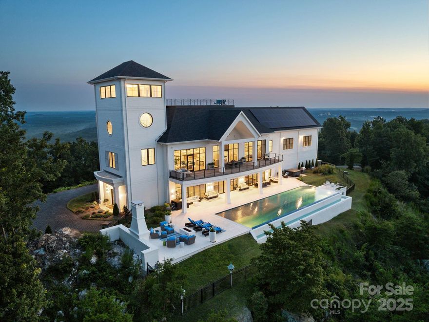 Situated on the highest peak in Randolph County, this 10,000 sqft custom-built home offers breathtaking views of the horizon. It features 44 acres, an infinity pool, outdoor fireplace, and a rooftop deck with sunset views. The main level includes 3 bedrooms, each with ensuite bathrooms and walk-in closets, along with a secondary kitchen and laundry room. Upstairs, the primary suite feels like a private retreat, featuring panoramic views, a spa-inspired bath, and an expansive dressing room. There is also another bedroom with ensuite bath and walk-in closet. The gourmet kitchen flows into a dining room and living area with fireplace, creating the perfect setting for both intimate evenings and large-scale entertaining. Other amenities include a home gym, 4 car garage, and exceptional views from every angle. Unparalleled craftsmanship throughout. From sunrise to sunset, this estate offers an unmatched lifestyle of privacy, beauty, and luxury, making it one of NC's most remarkable estates.