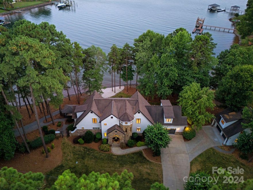 Vacation living at its best! Over 400 feet of water frontage awaits at this exquisite Lake Norman waterfront custom home. Freshly painted inside and out, and updated with top-notch finishes throughout, 213 Tuskarora Trail is a bright and airy retreat with plenty of natural light in every room. A gourmet kitchen features a lakefront dining area and makes entertaining a dream. The main-level primary suite offers stunning lake views and an updated primary bath with separate vanities. A unique second living quarters is above the detached two-car garage, perfect for guests or as an additional investment source. Experience the glow of the sunset from your backyard in this wide-open cove. Take in long-range views that go for miles, all from your sandy beach, or your back porch, patio, or private dock with a pier. The dock features a 10,000-pound boat lift covered with an awning, both new in 2021. There is room for a pool too!