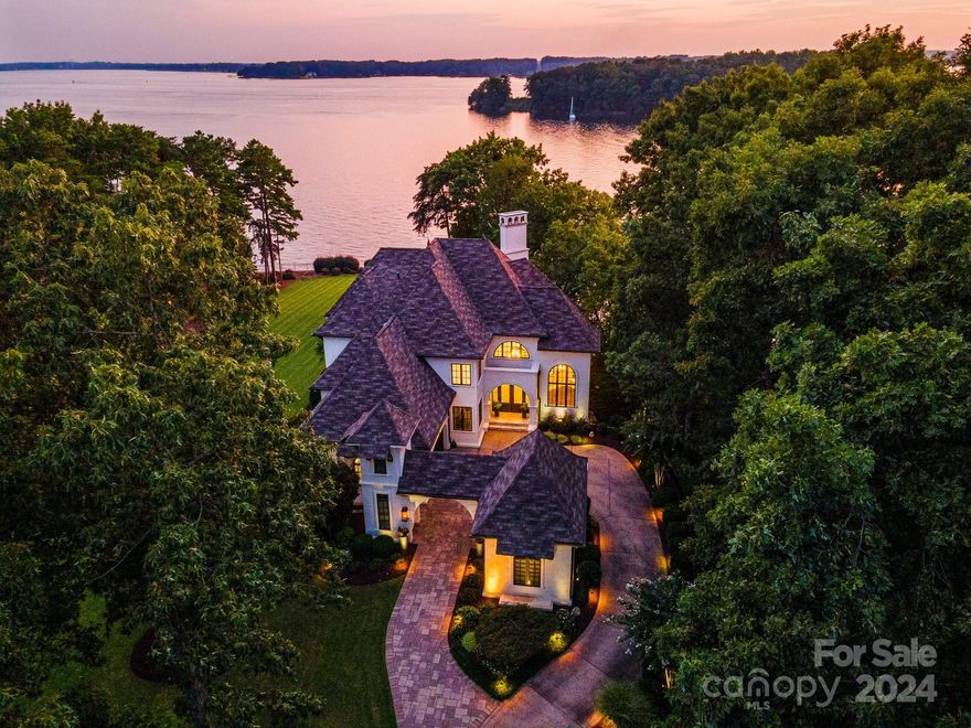 Exquisite, timeless and privately sited within The Peninsula, this custom home offers sweeping panoramic views of Lake Norman. Sunrise and sunset views abound, with attention to detail throughout. Renovated to perfection, gourmet chef’s kitchen with Wolf range and microwave, Sub-zero refrigerator, expanded island with luxury finishes, all open to the stunning cathedral great room with expansive lake views. Primary bedroom and spa bath on main level, study, and intimate living room. Covered balcony overlooks the pool deck, gardens, and pier. Second level offers three spacious bedrooms with ensuites. Lower level provides lake access, multiple entertainment areas, movie theater, bar, wine cellar, and bedroom. Cantilever umbrellas provide endless hours of outdoor leisure surrounding the pool, spa, and upper patio. Control4 audio, lighting, and security, generator, tankless water heaters and energy efficient upgrades throughout. Don't miss the chance to call this impressive estate home!