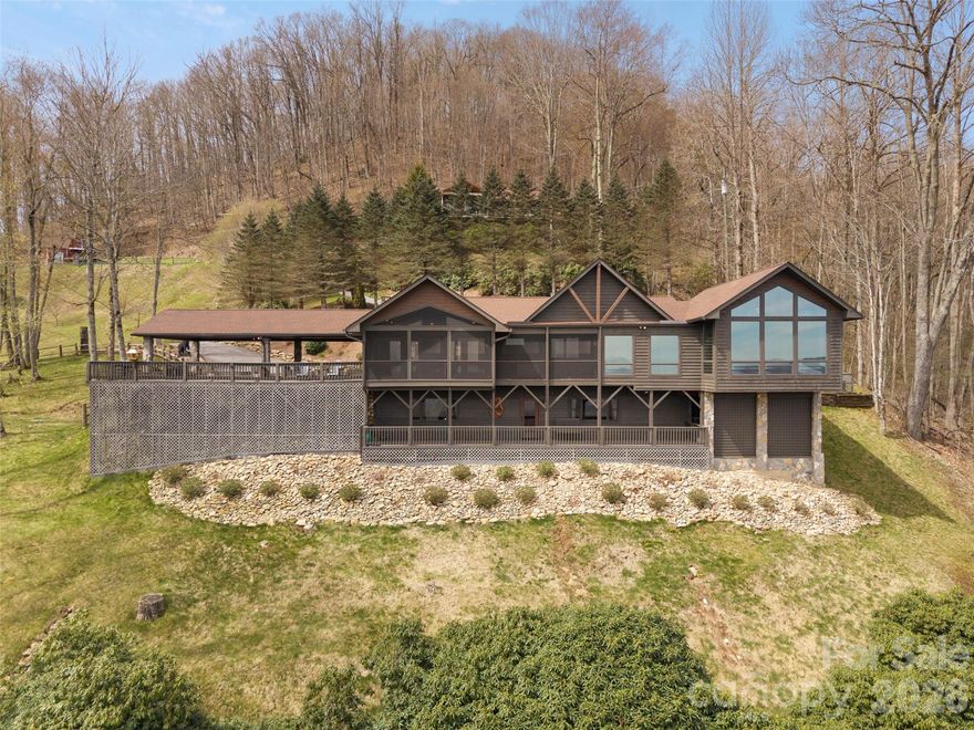 Perched high above it all in Walker in the Hills, this remarkable mountain retreat is designed for those who crave breathtaking views, effortless comfort, and exceptional spaces to gather. Expansive covered and screened porches invite you to slow down and soak in the long-range mountain vistas—perfect for morning coffee, evening sunsets, and everything in between. Inside, warm hardwoods, vaulted spaces, and a wall of windows create a light-filled atmosphere anchored by a stunning great room with a stone gas fireplace. The beautifully renovated kitchen is the heart of the home, ideal for entertaining with its oversized island, wine cooler, and seamless flow into the dining and living areas. The main-level primary wing offers a true sanctuary with its own fireplace, private sitting area, spa-inspired bath, and an extraordinary dressing room designed for both luxury and function. A second main-level suite ensures comfort and privacy for guests. The lower level expands your lifestyle, complete with a rec room, bar, additional kitchen, and flexible rooms for work, hobbies, or extended stays. Extensively renovated in 2021 with high-end finishes and meaningful system upgrades throughout, this home offers a fully updated and move-in ready experience. Surrounded by thoughtfully designed landscaping and complete with ample parking and a 3-car carport, this private mountain oasis offers the perfect blend of serenity, style, and everyday livability.