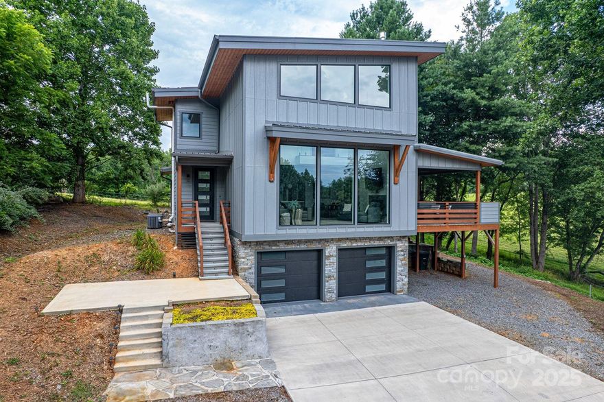 Ultra modern style home in Mills River! Large windows, two car garage, outdoor area with firepit. Covered deck.
Nice view of outside surroundings via large windows throughout. Living room with vaulted ceilings and fireplace. Spacious kitchen with gorgeous quartz countertops. Unique European cabinets. Large covered deck off dining room with rolling hill views. Upper level lends itself solely to the master suite featuring a large walk-in closet, double vanity and large tub and shower. Basement has plenty of storage and the two car garage.  Location is incredibly convenient to Brevard, hiking trails, Asheville, airport, and Hendersonville. A true rural setting with easy access to urban amenities. A horse farm borders the back of property creating a wonderful ambiance to relax and enjoy the outdoors whether by the firepit,  or on the porch. The location of this property would lend itself to making this a high end VRBO.