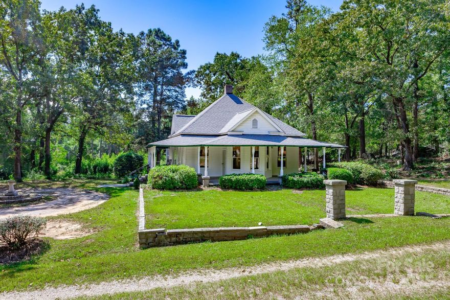 Imagine mornings on the wraparound porch with coffee in hand and the quiet satisfaction of calling a century-old farmhouse your own. Built in 1910, this farmhouse reflects craftsmanship and design that have stood the test of time. A meticulous exterior paint refresh highlights its graceful lines, while the wide porch seems made for rocking chairs, conversation, and lazy afternoons. Step inside and you’ll find historic details woven into every room, beadboard walls and ceilings, original hardwood floors, ceiling medallions, and three fireplaces that bring warmth and a sense of heritage. Even the two-door front entry hints at the stories this home has held for more than a century. In true farmhouse fashion, the home was designed for function and flow, with multiple exterior doors offering easy access from nearly every side. Two bedrooms on the right open directly outdoors, the dining room connects through a side entry, and twin front doors add a touch of historic charm and symmetry to the façade. The home features three bedrooms, each with its own character and flexibility. Two are generously sized, while the third connects to a short hall with a Jack-and-Jill bath on one side and a shared walk-in closet on the other, perfect for siblings, guests, or a home office with bonus space. The oversized kitchen and gathering room are ready to be reimagined, with newer LVP flooring already in place and sliding glass doors just waiting for the deck you’ve always wanted. Both bathrooms are modest in size and style but fully functional, offering plenty of opportunity for thoughtful updates. Out back, a wide open yard offers endless possibilities; a pool, guest house, garden, or lush entertaining area could all come to life here. It’s a blank canvas waiting for your vision and a touch of landscaping creativity. Set on 5 acres, this property provides ample space to stretch out, grow, and enjoy a slower pace. Priced at $315,000, it’s an invitation to own a farmhouse rich in character and ready for its next chapter.