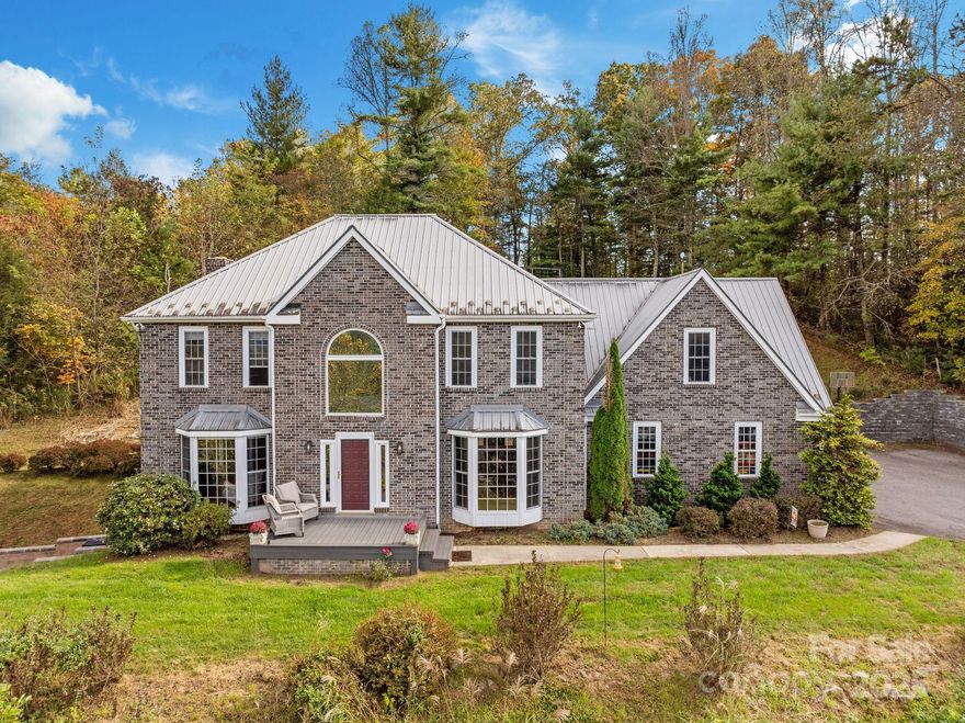 Perched atop a private rise in Madison County, this home captures the beauty and tranquility of mountain living, offering expansive 180° long-range views and breathtaking sunsets. A gently curving driveway leads through more than four acres of rolling, grassy landscape to a spacious 3,573-sq-ft residence designed for comfort, connection, and plenty of room to spread out.

The main level welcomes you with vaulted ceilings, a striking living room centered around a gas fireplace, and a kitchen that seamlessly flows into the dining area—perfect for entertaining or gathering with loved ones. Upstairs, the primary suite serves as a serene retreat, boasting mountain views, a generous walk-in closet, and a private en-suite bath. Two additional bedrooms, a full bath, and a large bonus room provide flexible spaces for work, play, or hosting guests. The finished lower level adds even more versatility, featuring areas ideal for an office, gym, or recreation room, complete with a woodstove and wet bar.

Outside, a two-stall barn with water and electricity is ready for hobbies, storage, or small livestock. Additional features include a whole-home generator hookup, fiber-optic internet, and zoned HVAC. With low Madison County taxes, no HOA, and easy access to both Asheville and Weaverville, this property offers peaceful, private mountain living at its finest.
