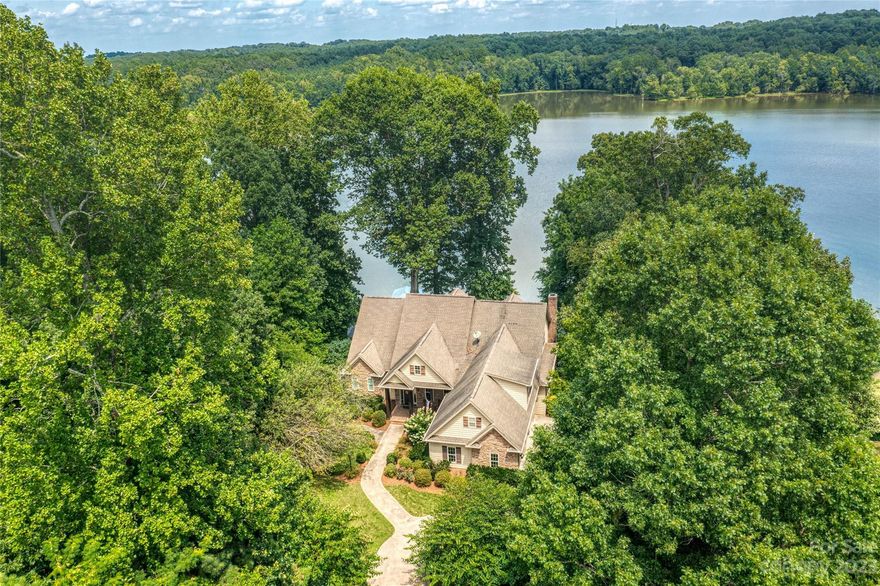 Breathtaking views of the serene cove and the lush botanical garden greenery across the water offers the ultimate experience of living on the Lake!  Exuding luxury, this home redefines elegance in every aspect of this pristine interior featuring coffered ceilings, beautiful hardwoods and a floor plan designed for entertaining and dining parties.  The gourmet kitchen with SS appliances, island and breakfast bar opens to dining and living room with water views and cascading sunlight.  Accommodating space with luxurious primary suite on main with 2 additional bedrooms plus additional bedroom, bonus and media on the upper level.  The impressive views continue outside to the covered patio, secluded hot tub and upper and lower decks.  Spending time on the water is a breeze with a floatation boat lift, jet ski float, kayaks and paddle boards!  There's even an RV setup with FULL service.  Come tour and see the views; your dream lake home search stops here - this is the one!