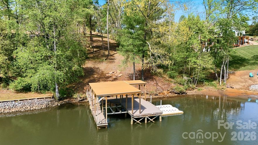 Experience the ultimate in lakefront luxury with this exclusive 2-ACRE WATERFRONT PROPERTY offering unparalleled privacy. Enter through the stately IRON GATE and follow your future private drive to the your personal lakeside retreat.  This exceptional homesite features 131 FEET OF SHORELINE, a CLEARED BUILDING SITE with SILT FENCE in place, 4 BEDROOM SEPTIC PERMIT, SHORELINE STABILIZATION permit, SAW SERVICE available for connection, and a CUSTOM TWO-STORY BOAT DOCK with DOOZI Boat Lift and jet ski ramp. Architect designed and engineered stamped house plans are available for an additional cost for a 4 Bedroom Saddleback-style residence designed to embrace the water views from every vantage point!  3 of the 4 bedrooms are suites.  There is more than enough room on the property for a 4 car garage/workshop. The land is ideal for entertaining, relaxing, or enjoying the tranquil sunsets that paint the water each evening. The building site is positioned to take advantage of the magnificent views of the expansive shoreline and serene natural setting, this rare property provides the perfect canvas to design your dream estate. A TRULY ONE-OF-A KIND OPPORTUNITY  to own a premier piece of lakefront paradise.  Enjoy North Carolina's 4 SEASONS!!  Spend the weekends on the lake & visit the NC Mountains in your spare time!!!  A little over an hour to Charlotte Douglas Airport!