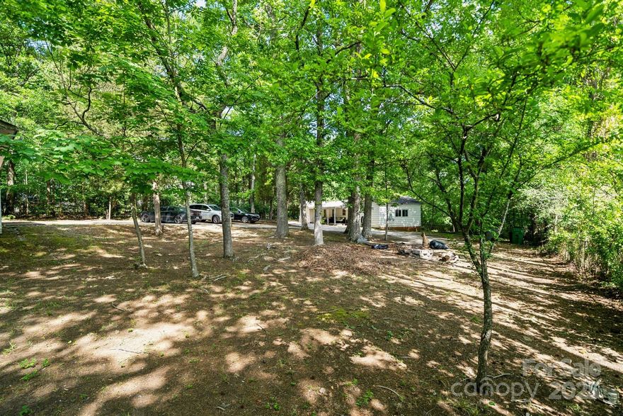 Over an ACRE in Charlotte with NO HOA. This two-bedroom, one-bath home is nestled on a deep sprawling lot for the perfect blend of privacy and space. Inside, the home has a cozy and comfortable layout, updated kitchen with granite counters, stainless steel appliances and original hardwood floors in living room and bedrooms. There is another large room with a closet that can be used as an office, flex space or bedroom. Additionally the property features a front and rear porch as well as an impressive garage workshop, measuring 864 square feet. This space is perfect for projects, hobbies, or additional storage. The property also presents an exceptional investment opportunity. The lot is surrounded by new construction and has the potential to be subdivided into two lots, you can explore the option of building duplexes or another home. Don't miss your chance to own this unique property in a sought-after location close to CLT Douglas Airport, 485, The Whitewater Center, 8 miles to UPTOWN!