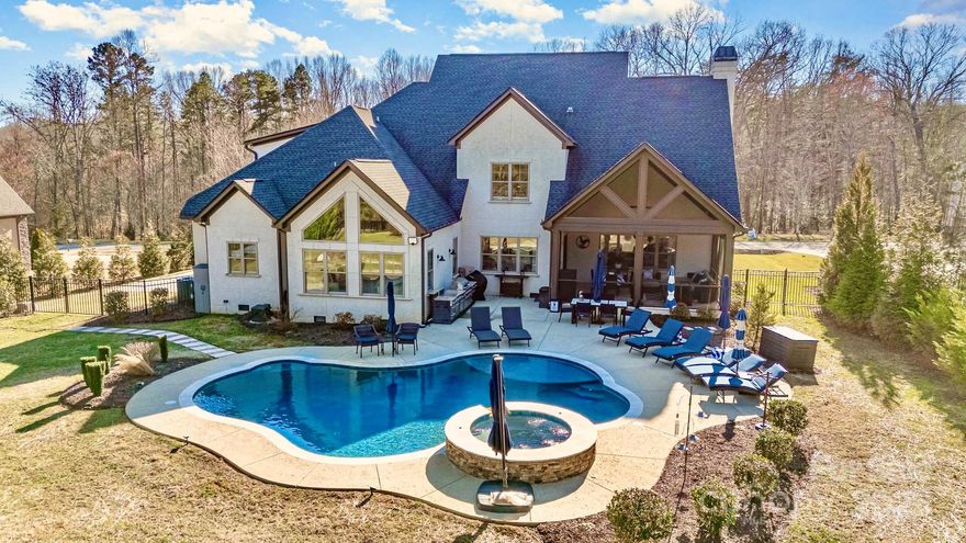 Welcome to Cobblestone, moments from Lake Norman, offering 4,900+ sq. ft. of luxury. From the rocking chair porch to the screened lanai overlooking your saltwater pool w/ hot tub & private half-court, every detail invites relaxation & recreation.
Gleaming hardwoods, arched entryways, soaring beamed cathedral ceilings, & stone fireplace w/ gas logs. The chef’s kitchen is a masterpiece boasting an eat-at island, commercial fridge, gas stove w/ pot filler, double wall oven, & breakfast nook, seamlessly connecting to the formal dining.

Impressive main-level primary suite features cathedral beamed ceilings, abundant natural light & serene pool views. Spa-like bath w/ soaking tub, cobblestone walk-in shower, dual vanities, & custom dressing room w/ wardrobe island, steps from the laundry. A 2nd bedroom & full bath complete the main level.

Upstairs, two full bedroom suites, an executive office w/ closet & en-suite bath, plus a theater/game room w/ wet bar. Whole house water filtration.