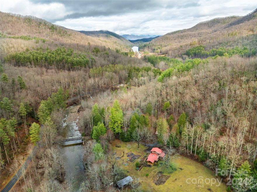 Bounded by state conservation land, with frontage on the trout waters of West Fork of the Pigeon River, this property offers an opportunity to embrace nature and luxury living. Lake Logan and Shining Rock Wilderness Area are close, and the Blue Ridge Parkway is a scenic 10 mile drive. The thoughtfully designed home offers an inviting space in harmony with the natural surroundings. Pristine springwater supplies the home, and native landscaping, gardens, and natural meadows beautify the grounds. A treehouse, featured on "Treehouse Masters,” serves as guest quarters. The covered picnic pavilion, with a fireplace, refrigerator and sink, is the perfect place for festivities, and the five RV campsites with hookups are a great option for visitors. This is a rare chance for a trout fishing retreat, outdoor enthusiast’s dream, or family getaway in the heart of WNC. For a 3D tour see https://shorturl.at/8wc2f (House) and https://shorturl.at/GcDUV (Treehouse). Video: https://tinyurl.com/3uxkfn8w