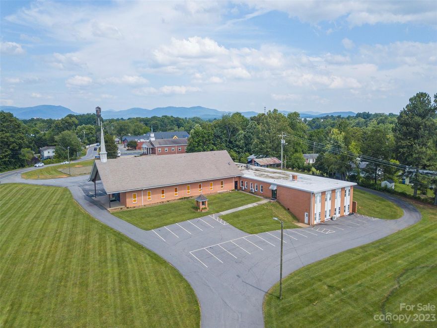 Remarkable church property in west Asheville in good condition. Spanning ~18,203 sq. ft., this site offers beautiful mountain views to the southwest. Stunning sanctuary with a wooden plank ceiling and state of the art lighting. Features include a full kitchen, multi-purpose room, lobby with gorgeous glass entry, spacious executive and admin offices, 2 sets of men’s/women’s bathrooms with multiple stalls, 11 classrooms, picnic pavilion, HVAC throughout, and ample indoor storage. There are 62 striped parking stalls, 3 dedicated handicap spaces and an overflow lot for 30 cars, as well as immaculate greenspaces, all on 3.71 acres. With institutional zoning, this could be a repurposed or redevelopment site for multifamily, destination venue, education, or many other specialty uses.