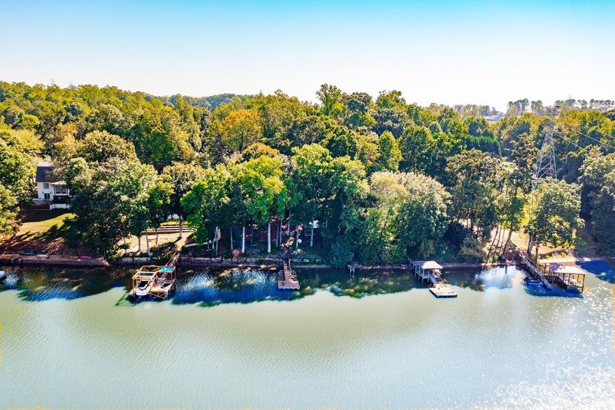 Just in time for summer, this oasis can be yours with 100 feet of lovely shoreline! Tucked down a private road, this home (1621 total square feet with basement) offers the feel of a real getaway, but with easy access to the airport and interstates. It's all about the water here... and as soon as you step inside, you see it! There's a kitchen w/ island, a dining room, and flex/lounge area. Two bedrooms and two baths on the main level, as well, including the primary bedroom w/ ensuite bath. The showplace of the house is the vaulted great room w/ expansive views to the lake. Downstairs, there's laundry and a bonus room (listed as 3rd bedroom by county) with access to the backyard. Ceiling height in the heated/cooled basement is just shy of 7 feet, so not counted in the overall heated living area, but great extra space. Relax on the back deck, the screened gazebo or on your private dock overlooking the water. Welcome home!