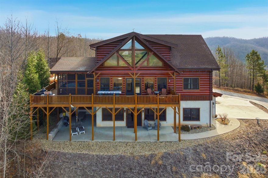 Welcome to your mountain sanctuary—where panoramic views meet modern luxury.
This custom-built three-story log home combines rustic charm with contemporary comfort, offering five bedrooms, six bathrooms, and an array of exceptional amenities. Whether you’re seeking a cozy retreat for two or the perfect gathering place for family and friends, this home delivers.
The main level showcases an open-concept living room, dining area, and chef’s kitchen, anchored by a soaring twenty-four-foot stone fireplace and floor-to-ceiling windows that frame breathtaking mountain views. The kitchen is a dream, featuring granite countertops, abundant cabinetry, two pantries, a wine cooler, two full ovens, a gas cooktop with telescoping exhaust, two dishwashers, and a wet bar—ideal for both everyday living and effortless entertaining.
The primary suite on the main floor offers stunning views, a spacious layout, and a spa-inspired en suite with a dual shower, multiple shower heads, and a jacuzzi bath with air jets perfectly positioned for soaking in the scenery. Upstairs, you’ll find two additional bedrooms with private or semi-private baths, along with a versatile loft space that works beautifully as a home office, playroom, or reading nook.
The lower level features a full in-law suite with two bedrooms, two bathrooms, a living area, kitchen, and its own laundry—perfect for multi-generational living or long-term guests. Entertainment and relaxation continue throughout the home, with a dedicated theater and recreation room, warm wood walls that create a true lodge-like atmosphere, and multiple living areas designed for both intimate evenings and large celebrations.
Outdoor living shines with a heated, screened-in deck, large fenced garden beds, and multiple covered seating areas. A wired, climate-controlled workshop with a man cave corner provides the perfect space for hobbies, projects, or unwinding, along with an additional workshop. Additional conveniences include dual laundry areas on the primary and lower levels, a garage, a carport, an EV charging port, an emergency generator hookup with a manual transfer switch, an outside connection for a hot tub, and abundant built-in cabinetry for storage throughout. For those seeking a seamless move, the home is also available furnished. 
Set within a private gated community, this property offers access to miles of nature trails, a stocked lake with a sandy beach, canoeing, swimming, and picnicking. It also features a pavilion with a large stone fireplace that serves as the heart of neighborhood events.
This home is the perfect blend of intimate comfort, expansive entertainment, income potential, fantastic craftsmanship, and additional features that you must see in person to appreciate fully. Schedule your private showing today and experience mountain living at its finest.