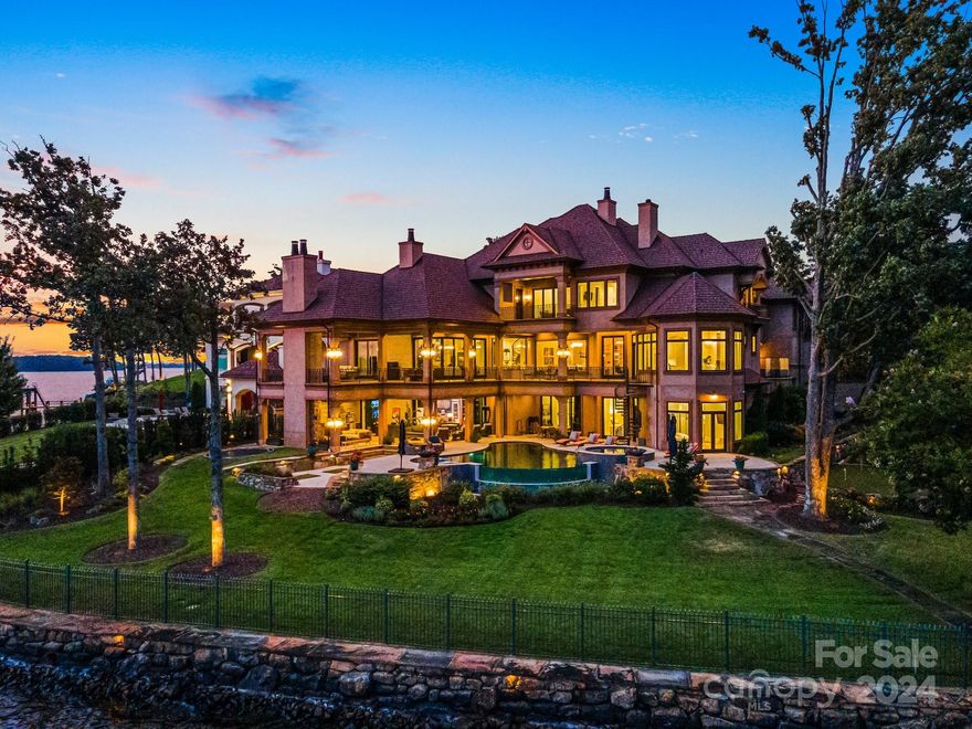 Experience privacy and luxury in this exquisite custom estate, nestled on a point lot with over 300’ of shoreline and breathtaking Lake Norman views. Main residence captures the essence of warmth and sophistication with 6 well-appointed en-suite bedrooms, spectacular spiral staircase, slide, elevator, and unsurpassed craftsmanship. An entertainer's paradise created to seamlessly blend the outside and inside; retractable stacking doors on covered terrace and patio, multiple great rooms, enviable equestrian movie theater, golf simulator, resort-like pool with infinity glass edge, spa, fire pit, sunken trampoline, putting green, pier, covered boat house, 6-car garage, generator, and pet room. Cathedral beamed kitchen boasts dual islands, Wolf range, glass door Sub-Zero fridge, scullery, and expansive pantry storage. Second living area above garage, gated entrance, Control 4 automation, energy efficient features throughout. Don’t miss the opportunity to enjoy this truly magnificent home!