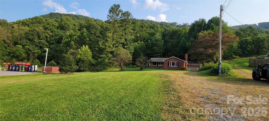 POTENTIAL BUSINESS OR RESIDENTIAL DEVELOPMENT INVESTMENT - THIS 6.8 ACS with road frontage off 4 lane Dellwood Rd is located 5-7 minutes from Lake Junaluska/Waynesville & Maggie Valley.  Currently on public water with potential sewer availability w/Town of Maggie Valley approval.  Property not currently located inside city limits, but adjacent properties on each side are in city limits with publc water/sewer per Town of Maggie Valley associate panner, if divided or developed, buyer could potentially leave rear 4-5 acres in Haywood Co. and annex only the front portion inside the city limits, if desired.   Property includes approx 1250 SF 2 Br/2 Bh partial brick home w/rear garage w/add'l 1/2 bath.  Home being sold in 'AS IS' condition.  With repairs/updates home could/potentially make a commercial office or residence. The front of property is almost level with 2 state curb cuts for loop driveway or 2 separate driveway entrances.  Property behind QP station is included with 6 acres of vatious development potentional.  Plat recorded in Cab B, page 95 Haywood County NC also appear to show a 24 ft shared ROW/driveway with neighbor on right.  One state curb cut is near QP station.  Brick home has separate curb cut with grassy/gravel driveway.  Width of property near middle is approx 500 ft in width per attached Haywood County aerial.  Seller will consider part owner financing with 50% down.
