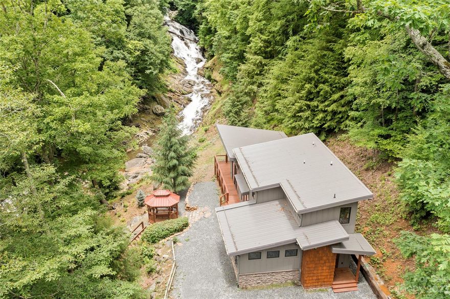 Rare Offering for a magnificent 200-ft cascading WATERFALL, 1,000 ft of Howard's Creek frontage, & a new (C/O issued '23) Mountain Modern home on 4+ acres in close proximity to Boone! Short-term rentals permitted=investment potential! Perfect as a getaway or vacation rental w/ views & sounds from one of the most spectacular waterfalls in the High Country from inside the home & out! A trail leads from the home along the designated Blue Ribbon Trout Stream to a natural pool at the base of the waterfall. Home features all main living on the WALK-IN LEVEL & has easy access year-round. Open-concept floorplan w/ 2 suites, wood accents, T&G vaulted ceilings, pine beams. Enjoy waterfall views from large deck & from floor-to-ceiling windows in Great Room. Primary suite on main features walk-in closet & heated floors in bath, & loft/office space could function as 3rd sleeping area (3BR potential if buyer expanded septic). Also featuring: covered entry, security system, gazebo/firepit area, shed.