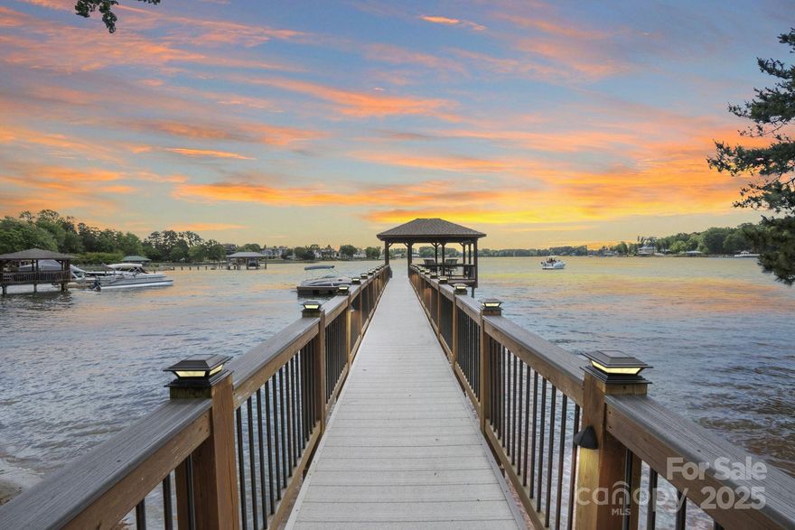 Rare Lake Norman Gem! Don't miss this extremely rare chance to own a true waterfront retreat on over 1 acre in Cornelius, nestled in the desirable Peninsula community but with no HOA restrictions. Enjoy the peaceful beauty of Lake Norman with lush landscaping, a natural sandy beach, and a private, level backyard ideal for entertaining. Relax on the oversized covered deck with remote shades or gather on the spacious patio. This 5,700 SF home offers 2 luxurious primary suites (main & upper level), a sunroom with stunning lake views, a media/bonus room with a kitchenette, 3 very spacious guest rooms & a gym.  Extremely well cared for, recent upgrades include new roof (2023), windows (2020), luxury vinyl & tile flooring, kitchen appliances (2021), privacy fence (2020), Leaf Filter gutters (2023), new attic insulation, sealed crawlspace & more. Lake activities await with the Private pier, a covered sitting dock area & HydroHoist boat Lift. A blend of quality living, privacy & convenience!