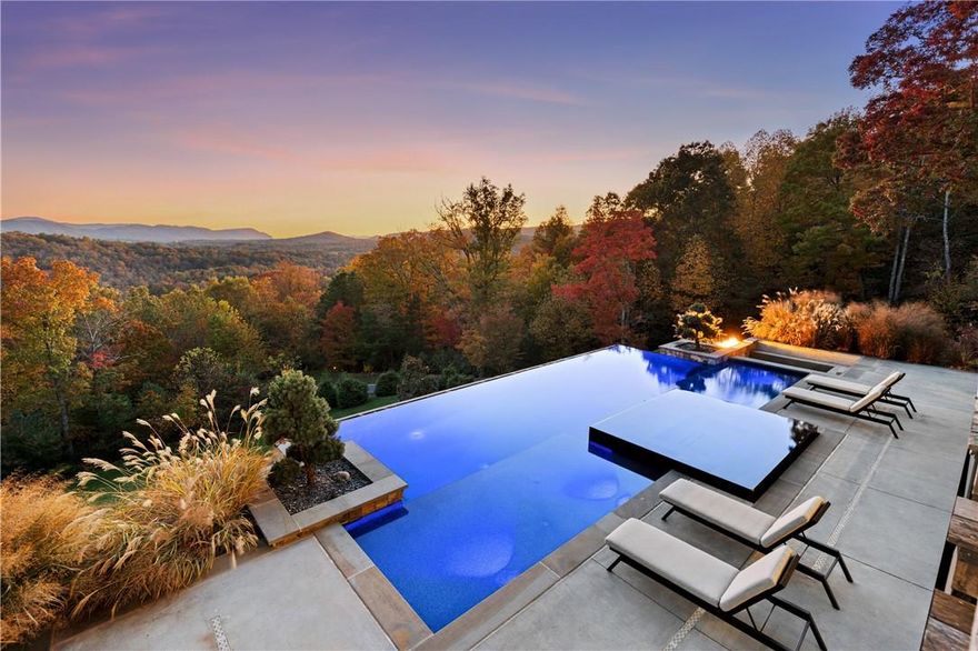 Seek serenity within the 26+ acre estate minutes from Asheville that envelopes you in awe-inspiring mountain views from sunrise to sunset. The award-winning 11,682 SQ FT residence offers an Industrial-Chic design with globally inspired finishes. The consummate entertainer’s trophy, the property is designed as a true oasis, where everything desired exists. Main and upper levels read modern with clean, sleek lines mingled with warm natural elements. The lower level gives Art Deco extravagance in the full bar with lounge, a billiard room and theater. Dramatic 25-foot ceilings, waxed steel beams, Brazilian quartzite with double waterfall edges, executive-level appliances, midnight-blue primary and sunrise-welcoming primary bath, edgeless pool & spa, outdoor fireplaces and grills, marked trails, expansive decking w/ retractable screens are notable features. Additional home on property is an updated 3 bed/2 bath ranch. Estate contains 3 parcels of land; drawings of 2nd guest house available.