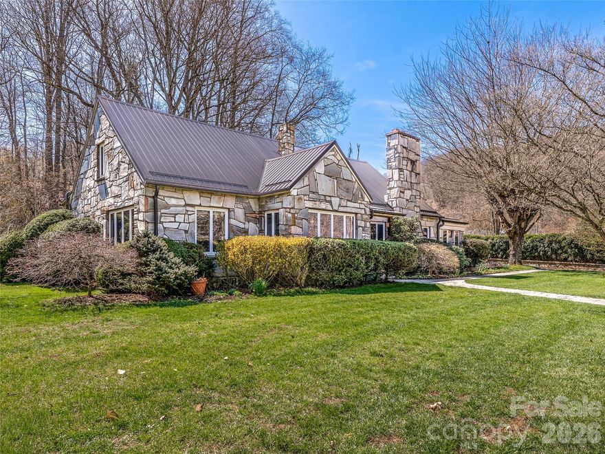 Stunning riverfront English stone cottage with guest apartment, set against breathtaking mountain views. This exceptional private estate blends timeless charm with expansive living across four level acres. Inside, you’re welcomed by original hardwood floors, handcrafted wood paneling, and meticulous attention to detail throughout. The large eat in gourmet kitchen, sun-drenched porch, and bright sunroom with stone floors create a warm yet refined living experience. This cozy mountain home offers plenty of room to live, work and play. Charming garage apartment is fully furnished and ready to host guests or to be used as an income generating rental.

Outdoors, the property transforms into a private retreat featuring 500 feet of stone walls, a sprawling backyard with private hot tub, and an impressive screened pavilion complete with outdoor kitchen and fireplace—perfect for entertaining. The beautiful large barn is ready for your imagination. Plenty of space for gardening or a small farm.  Relax, fish for mountain trout or swim in the picturesque river. A brick-paved driveway and walkways, elegant landscaping, and a serene pond complete this one-of-a-kind offering. Minutes to downtown Burnsville, just 45 minutes outside of Asheville.