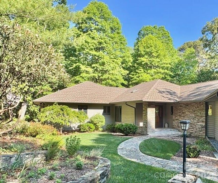 Step into this Kenmure home that feels like a private retreat, where every detail invites peace, relaxation, and connection with nature. Surrounded by lush laurels and mature landscaping, the property evokes the charm of a mountain escape, complete with walking paths, a gentle stream, and a soothing man-made waterfall—perfect for unwinding as you listen to its calming sounds, even from the primary bedroom and bath. Inside, walls of windows create a light-filled, treehouse-like atmosphere that brings the outdoors in. Enter through a striking foyer with Australian lacewood and marble flooring, opening into a spacious, serene interior that flows seamlessly to the surrounding natural views. The main level offers approximately 3,100 square feet of open-concept living, featuring beautiful hardwood floors, expansive spaces for entertaining, and cozy areas to relax by the fire or with a good book. The chef’s kitchen is both functional and inviting, with a large island, Thermador gas stove, and Sub-Zero refrigerator. Butler’s pantry provides additional storage and prep space. Designed for convenient main-level living, the home includes a luxurious primary suite with dual vanities, a walk-in tiled shower, soaking tub, and generous walk-in closet, along with a main-level laundry. The lower level provides flexible guest space, a workshop, mudroom, and ample storage. Outdoor living shines with a beautiful deck featuring cable railing for unobstructed views, including seasonal winter mountain vistas, while the evergreens offer year-round color and privacy. New roof (2022), updated HVAC, whole-home generator, abundant storage, and both upper and lower garage bays, this home blends thoughtful upgrades with natural beauty—creating a truly peaceful retreat.