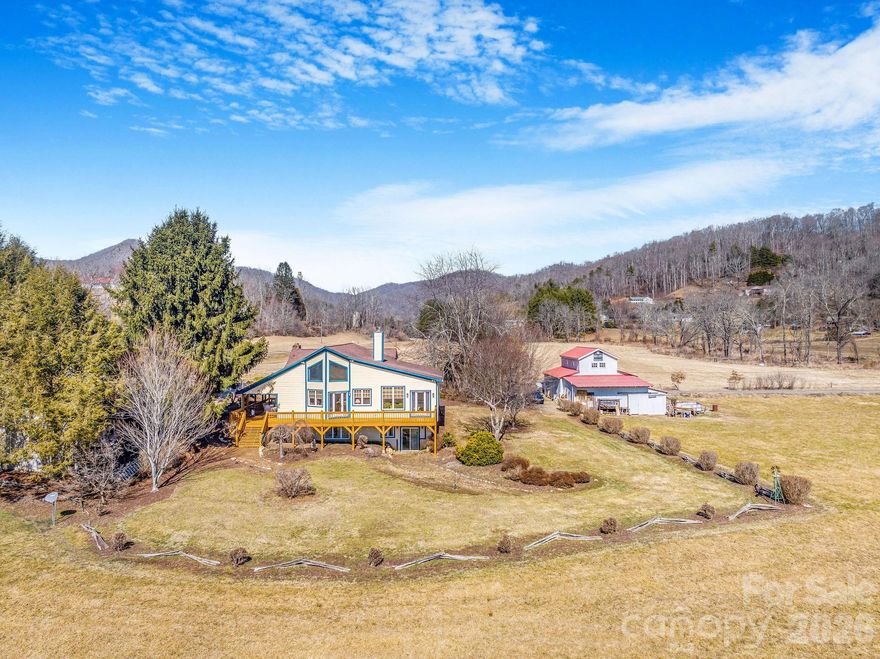 Set on approximately 4.5 private acres in Canton, this thoughtfully expanded 1947 stone cottage offers both convenience and retreat — just minutes to I-40 for easy access to Asheville and Waynesville, yet tucked away in a peaceful natural setting.  Between 2006-2007, the current owners carefully preserved the character of the original 2BR/1BA home while adding over 2,200 square feet of living space, resulting in a spacious 4-bedroom home with office and 3.5 baths (additional 1 bed + 1 bath accounted for in listing is the garage apartment). Original flooring and trim remain in beautiful condition, blending seamlessly with custom finishes throughout.  The main living area features vaulted ceilings, abundant natural light, open dining space, and a striking double-sided wood-burning fireplace shared with the primary suite. The generously sized primary bedroom opens to the expansive front deck, positioned to capture light while maintaining privacy.  The lower level offers a second living area, bedroom, and full bath — ideal for guests, multigenerational living, or flexible use.  Beyond the main residence, the property includes a detached two-car garage with a one-bedroom apartment (tenant in place; lease details available) providing income potential. A two-story barn with tractor storage and workshop space sits alongside pasture areas suitable for a variety of uses.  This unique property offers space, flexibility, and opportunity — a rare combination of privacy, character, and functionality for those seeking more than a traditional neighborhood setting.  Portion of the home footprint is in the flood plain & seller carries flood insurance.