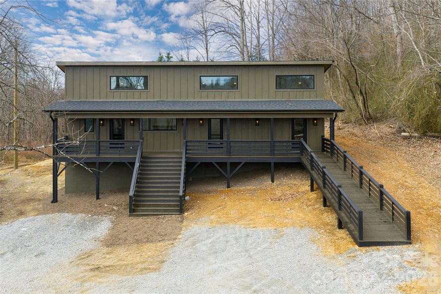 In a peaceful setting just outside Hendersonville, this newly constructed mountain-modern home offers a rare combination of flexibility, comfort and income potential. Thoughtfully designed with clean lines and an open, light-filled layout, the property is configured as two private residences, a two-bedroom, two-bath and a one-bedroom, one-bath, with a pre-framed interior doorway that could be opened through simple drywall removal to create a three-bedroom, three-bath single-family home. Both units feature soaring 16-foot ceilings, large clerestory windows, durable LVP flooring, leathered granite countertops, soft-close cabinetry, stainless steel appliances, and electric fireplaces that add warmth and ambiance. Zoned mini-split heating and cooling, in-unit washers and dryers, and spacious closets with built-in systems enhance everyday livability. A gracious covered front porch spans full length of the home and offers stair and ramp access, making the design especially well-suited for age-in-place or multi-generational living. Positioned above the road near blooming apple orchards, charming flower farms and scenic vineyards, the property enjoys privacy and seasonal winter mountain views, along with generous crawlspace storage. Conveniently near local schools, hospitals, and just minutes from downtown Hendersonville, Asheville Regional Airport and Asheville, this property is ideally suited for investors, short-term or long-term rentals, extended family living or a flexible owner-occupied lifestyle.