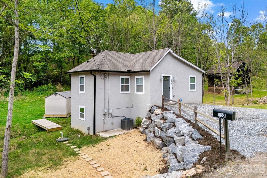 Tucked onto a private acre of paradise just minutes from Mars Hill and Mars Hill University, this enchanting French-inspired cottage pairs timeless charm with modern turnkey convenience. Built of solid cinder block for enduring strength, the home is framed by lush acreage naturally shielded by a rim at the rear—an idyllic, storybook setting perfect for quiet afternoons, games of horseshoes, or even target practice in serene seclusion.

A gentle creek meanders through the property, its steady song offering peace in every season. Even during Hurricane Helene, the waters remained safely within their banks. Picture yourself on the covered deck, sipping morning coffee as you listen to the creek flow, or enjoying crisp fall evenings wrapped in privacy and nature’s embrace.

Fully renovated in 2022–2023, the home offers peace of mind with a new roof, mini-split HVAC, septic, windows, plumbing, electrical, luxury vinyl plank flooring, designer lighting, and a beautifully refreshed kitchen. It’s truly move-in ready—cozy, inviting, and built to last. With its character and updates, it suits many lifestyles: a full-time residence, a romantic mountain escape, a student or faculty rental, or a high-appeal short-term rental.

The location is exceptional. Just a few miles from I-26, you’re moments from Mars Hill University and a short drive to Weaverville, Hot Springs, and Asheville’s vibrant culture. For investors, proximity to the university means strong rental demand from families, faculty, and campus visitors. For adventurers, opportunities abound: skiing at nearby Hatley Pointe, hiking the iconic Pisgah National Forest and Blue Ridge Parkway, tackling Big Bald on the Appalachian Trail, or chasing waterfalls like Looking Glass Falls and Sliding Rock. Cultural experiences thrive too—enjoy live performances at the Southern Appalachian Repertory Theater, adrenaline at Bailey Mountain Bike Park, or local charm in downtown Mars Hill with its galleries, boutiques, eateries, and seasonal festivals. Madison County also offers horseback riding, breweries, wineries, and the restorative hot springs that give the nearby town its name.

Mars Hill delivers the best of both worlds: small-town mountain living with big-city access. In less than 20 minutes you can be in Asheville, renowned for its food scene, arts, music, and shopping—before returning home to the quiet beauty of your own private sanctuary.

This is more than a home—it’s a lifestyle. A place where craftsmanship, nature, and opportunity converge. Whether you dream of cozy nights by the fire, gathering friends for weekends in the mountains, or creating a profitable investment property, this cottage provides the backdrop for memories and moments that will last a lifetime.