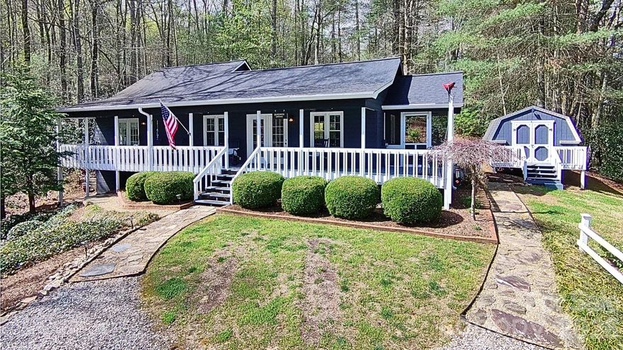 Tucked into 4.46 private acres along Camp Creek Road in Saluda, this two-bedroom, two-bath mountain cottage is the kind of place that stops you the moment you pull in. The sound of the creek carries across the property, setting a melodic tone that's both peaceful and hard to leave behind.

The covered front porch runs the full length of the home, fitted with ceiling fans and plenty of room to gather. When you want nature even closer, a separate screened porch gives you that connection without the tradeoff. Both spaces invite the kind of slow mornings that mountain getaways are made for.

Inside, vaulted ceilings and warm hardwood floors run through an open-concept living, dining, and kitchen layout that feels spacious without being oversized. The kitchen features stainless appliances and stone counters — updated, functional, and easy to enjoy right away. The furnishings carry a cohesive mountain cottage character throughout, and they're negotiable with the sale.

A large, detached storage shed sits on the property, ready for tools, gear, or whatever a life well-lived in the mountains requires. The mature plantings surrounding the home deliver real seasonal beauty, especially in spring with the azaleas and mountain laurel in bloom.

When you're ready to venture out, downtown Saluda's charming shops, eateries, and small-town character are under five minutes away. Vibrant downtown Hendersonville — boutiques, restaurants, breweries, and year-round events — is about twenty.

Private. Peaceful. Turnkey. And closer to everything than it feels.