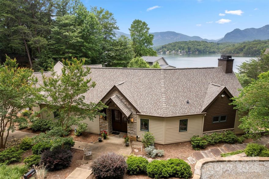 Step into this luxury waterfront retreat, boasting awe-inspiring western views of the majestic Hickory Nut Gorge. This immaculate home offers unparalleled main level living, seamlessly blending elegance with comfort.The inviting open floor plan welcomes you with warm wood floors, accent beams, & a striking gas stone fireplace with a chef's kitchen featuring a massive granite island, abundant cabinets, & top-of-the-line appliances. Retreat to the primary bedroom complete with a lavish en-suite bathroom & a walk-in closet . Adjacent, a spacious office area while the main level laundry room adds practicality to daily chores. Attached 2-car garage and ample additional parking for guests. The downstairs family room features a gas stone fireplace along with 3 additional bedrooms each boasting breathtaking views of the surrounding landscape. Step outside to the meticulously manicured yard, where a beautifully landscaped terrace leads to the rooftop deck & boathouse equipped with a boat lift.