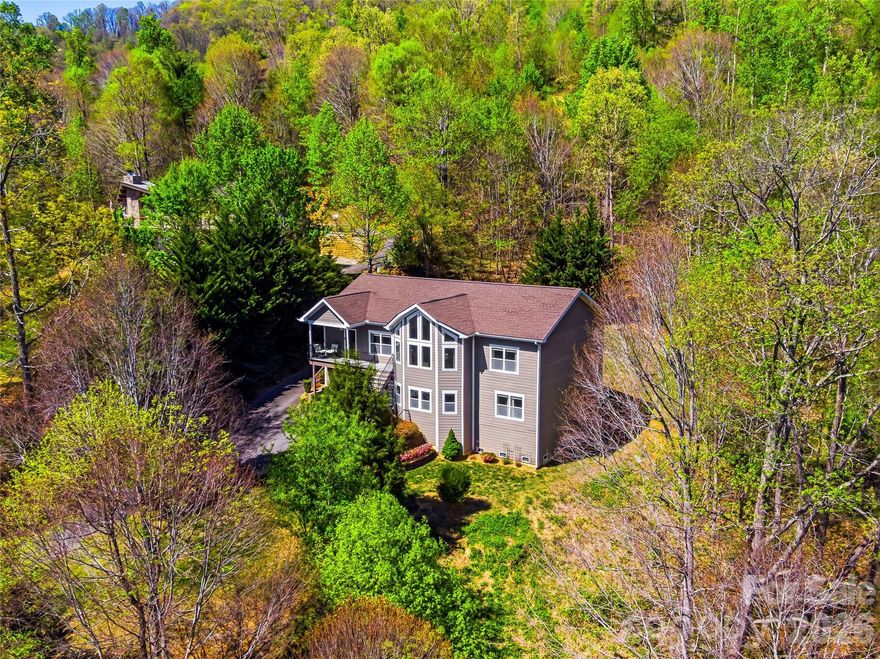 Wait until you experience the stunning year-round, long-range southern views from this exceptional 4-bedroom, 3-bath modern contemporary home. Nestled in a short-term rental acceptable neighborhood located just 10 minutes from West Asheville and under 20 minutes to downtown. This home offers both convenience and tranquility with ample storage and a bonus room office space on the main level. Designed for modern living, the open floor plan features a spacious, light-filled living area with vaulted ceilings and breathtaking sunrise views. The expansive kitchen is a true centerpiece, showcasing a large island, sleek quartz countertops, clean-lined contemporary cabinetry, and abundant pantry storage. The main level—conveniently accessible with parking at the rear—also includes a formal dining room and generous living space perfect for entertaining or relaxing. Downstairs, the home offers a versatile 2-bedroom apartment with a private entrance, full kitchen, and an oversized family room—ideal for guests, rental income, or multigenerational living. Located in a prime community with easy access to everything Asheville has to offer, this property truly combines style, space, and an unbeatable setting.