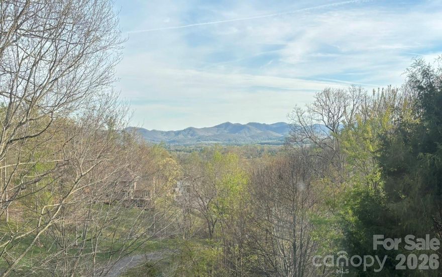 Wait until you experience the stunning year-round, long-range southern views from this exceptional 4-bedroom, 3-bath modern contemporary home. Nestled in a private and peaceful neighborhood located just 10 minutes from West Asheville and under 20 minutes to downtown. This home offers both convenience and tranquility with ample storage and a bonus room office space on the main level. Designed for modern living, the open floor plan features a spacious, light-filled living area with vaulted ceilings and breathtaking sunrise views. The expansive kitchen is a true centerpiece, showcasing a large island, sleek quartz countertops, clean-lined contemporary cabinetry, and abundant pantry storage. The main level—conveniently accessible with parking at the rear—also includes a formal dining room and generous living space perfect for entertaining or relaxing. Downstairs, the home offers a versatile 2-bedroom apartment with a private entrance, full kitchen, and an oversized family room—ideal for guests, rental income, or multigenerational living. Located in a private community with easy access to everything Asheville has to offer, this property truly combines style, space, and an unbeatable setting.