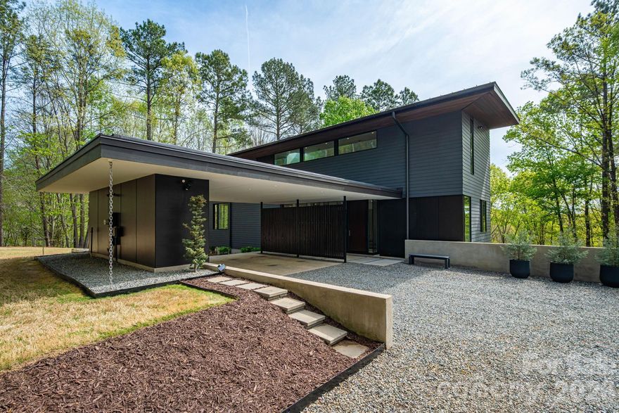 Where Architecture Meets the Water's Edge

 

Some homes are simply places to live. This one is an experience — a multi-award-winning architectural masterpiece where modern minimalism, nature, and lakefront living converge in extraordinary harmony. Poised on more than ten wooded, private acres with over 200 feet of unspoiled shoreline, this residence offers a rare kind of freedom: total privacy, total connection.

 

Step inside and the outside follows you. Commercial-scale glass windows and walls dissolve the boundary between interior and landscape, flooding every room with endless water and woodland views. The open floor plan flows naturally — perfect for quiet mornings, effortless entertaining, and everything in between. Enclosed gas fireplaces anchor both the main living room and lower den, offering warmth and ambiance year-round.

The chef-designed kitchen is a study in precision: Bosch, Braun, and Wolf appliances paired with custom extra-deep, soft-close wood cabinetry and waterfall granite countertops. Every surface considered, every detail intentional. A large media room is perfect for movie nights, and the open plan makes hosting feel effortless.

 

Each bedroom is a private retreat, fully ensuite with soundproof walls between spaces — ensuring privacy and quiet are never an afterthought. The east-facing primary suite feels like sleeping in the tree canopy itself, waking to morning light filtering through the leaves. Its Zen spa bathroom features heated floors, a freestanding volcanic limestone soaking tub, dual sinks, and a generous glass shower.

 

Outdoors, life expands. A huge deck with powered awning, open patio, and private covered porch create seamless spaces for gathering or solitude. Your private permitted dock — with boat slip, generous seating areas, and a peaceful cove setting — makes every day on the lake effortlessly yours. A mile of wooded trails wind through the property for morning walks and evening escapes.

 

Thoughtfully built for the future: plumbing stub-ups support an additional full bath and expansion of an existing half-bath, while a large unfinished storage and mechanical room offer room to grow. A fully integrated, hidden network on a dedicated internet line keeps the home seamlessly connected — invisibly, as it should be. Highly efficient materials and construction keep energy costs impressively low.

 

This is not just a home. It is a private world — award-winning, waterfront, and entirely your own.