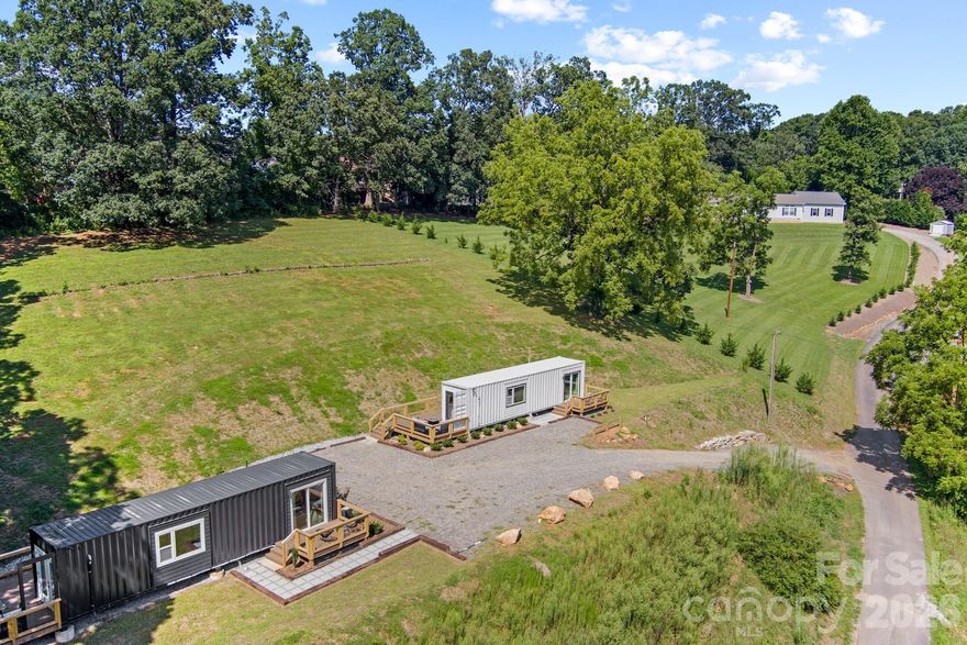 Own a rare modern container retreat just minutes from Asheville—featuring two designer turnkey tiny homes (fully furnished), Pearl and Onyx, with added development potential and city utilities already in place.

Pearl and Onyx Container Homes present a distinctive opportunity to own two thoughtfully designed modern container homes while also securing a highly usable homesite in a desirable location. With city water and city sewer already connected, the property offers flexibility for future expansion, redevelopment, or building a larger custom home while maintaining the existing structures.

Each home showcases contemporary design with efficient, low-maintenance living, including sleek kitchens, well-appointed full baths, and curated interior finishes. Outdoor living is a standout feature, with spacious decks ideal for relaxing, entertaining, or enjoying the surrounding mountain setting, along with private bedroom decks for added outdoor space.

Whether you choose to maintain both homes as a short-term rental investment, live in one and rent the other, or utilize them as guest accommodations for a future primary residence, the options here are rare and versatile. The existing homes can remain as part of a larger vision or be removed to fully maximize the property’s potential.

Located just minutes from Asheville’s dining, shopping, breweries, and outdoor recreation, this property combines immediate usability with long-term development potential—an increasingly hard-to-find opportunity in Western North Carolina.