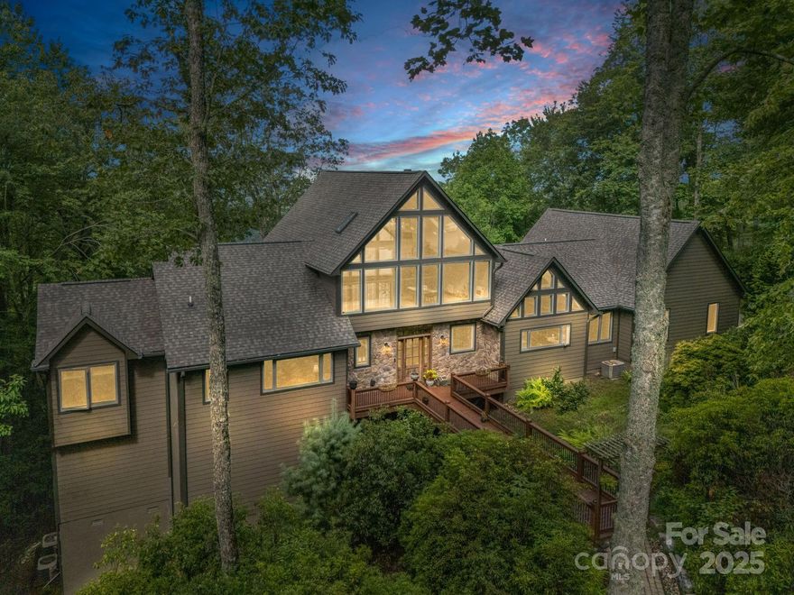 This stunning custom home in Connestee Falls was thoughtfully designed to showcase long-range, layered Blue Ridge Mountain views from nearly every room. Sitting on 1.6 acres at the end of a quiet, level dead-end street, it offers over 4,800 heated sq ft of bright, open living space. Fully renovated in 2019, the home features an updated kitchen, all four full baths, modern fixtures, fresh finishes, and more. The main level features a gourmet kitchen with granite, stainless appliances, hardwood floors, a spacious primary suite, bonus room/office, and 2 full baths. The walkout lower level includes a full living area, kitchenette, 2 bedrooms, 2 full baths, bonus room, exercise room, and storage. A soaring upper-level loft accessed by a custom wood spiral staircase offers inspiring views and endless possibilities. With multiple fireplaces, a screened porch, expansive deck, attached garage, generator, and more—this home defines luxury mountain living in Connestee Falls.