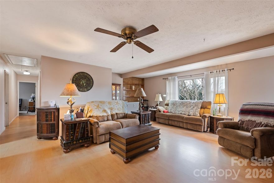 Location truly sets this one apart—just minutes to town, yet offering space, flexibility, and standout features you won’t find everywhere. A welcoming wrap-around porch and dual driveways create both curb appeal and everyday convenience, with easy access to each level of the home. Inside, the main level features an open-concept kitchen, living, and dining area anchored by a cozy fireplace, along with three bedrooms, two baths, and a laundry room. Step out onto the expansive wrap-around porch—both covered and open—for effortless indoor-outdoor living, whether it’s morning coffee or evening unwinding. What really elevates this property is the fully self-contained second living quarters on the lower level. Complete with its own kitchen, living room with gas log fireplace, bedroom, bath, laundry, and separate interior and exterior entrances, it’s perfectly suited for rental income, guests, or multi-generational living. Additional perks include no HOA, no city taxes, Spectrum high-speed internet and TV, city water and sewer, and ample parking with dual driveways and a lower-level carport. The gently sloped, sunny yard also offers two workshop/storage buildings for hobbies or extra space. With a metal roof (2019) and added climate control options, this home blends comfort, practicality, and versatility in an unbeatable location.