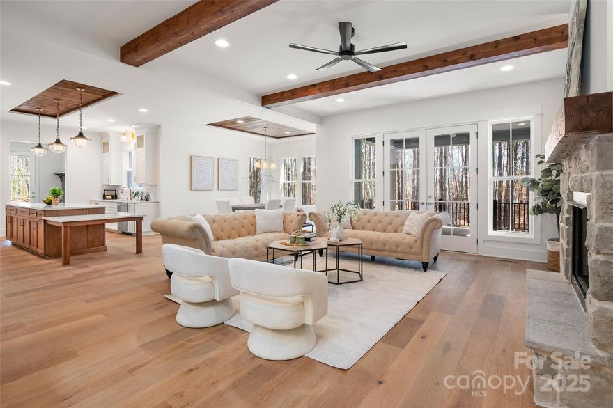 Welcome to 157 Silver Falls Drive, an extraordinary modern farmhouse in the sought-after Falls Cove community of Troutman. Nestled on a private one-acre lot, this newly built 5,079 sq. ft. masterpiece blends timeless craftsmanship with today’s most desirable features.

Step inside and you’ll immediately notice the wide-plank hardwood floors and detailed trim work. The main level offers a private office with custom built-in shelving, while the open living area is enhanced by exposed wood beams and striking ceiling details. The chef’s kitchen showcases custom cabinetry, a built-in panel-faced refrigerator, a 36-inch gas cooktop with a custom hood, and a massive multi-level island perfect for both seating and cooking. A spacious walk-in pantry with built-in shelving completes this dream kitchen.

The first-floor primary suite is a retreat of its own, featuring a cozy fireplace, exposed beams, and a spa-inspired bath with a freestanding soaking tub, zero-entry shower, and expansive custom closets with built-in organizers—including a private washer and dryer.

Upstairs, you’ll find three oversized bedrooms with hardwood floors, custom bathrooms, and walk-in closets with organizers. Two generous bonus rooms on this level offer incredible versatility—ideal for multiple home offices, a theater, gym, or playroom. An elevator services all three levels, leading up to the third floor, where you’ll find another expansive flex/bonus space that can easily be tailored to your needs.

Outdoor living is just as impressive, with a covered concrete patio and stone fireplace overlooking the peaceful surroundings. The backyard offers plenty of room to accommodate a pool, creating the ultimate private retreat. The oversized 3+ car garage includes epoxy flooring and extra-deep bays, ideal for auto enthusiasts, storage, or a workshop.

Every detail of this home reflects thoughtful planning and superior craftsmanship. For buyers who prefer a different look, the builder is willing to paint the exterior to match the original white rendering—ensuring the home perfectly fits your vision.

Located just minutes from Mooresville and Troutman, this home sets a new standard for modern farmhouse living. Impeccable in every way, it will stand tall against anything else you may tour. This one must be seen to be fully appreciated.