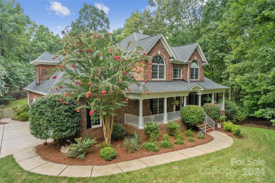 This custom retreat on nearly 2 wooded acres offers unmatched privacy with lush landscaping. An impressive driveway leads to a full-brick home in Lake Wylie, featuring hardwood floors, custom cabinetry, and crown molding. The entertainer’s kitchen includes granite countertops, stainless steel appliances, a massive center island, an eat-in area, and a walk-in pantry. The family room, with built-in bookcases, a fireplace, and coffered ceilings, opens to a large screened-in porch overlooking the private, wooded backyard, ideal for a pool. The main-level primary bedroom features a double trey ceiling, a sitting area, and an ensuite bathroom with double sinks, double closets, a Jacuzzi tub, and a tiled shower. Upstairs are four bedrooms, including one with an ensuite bathroom, plus a bonus room. The three-car side-load garage has space for a workshop or golf cart. In a no-HOA neighborhood, this property blends privacy, luxury, and convenience.