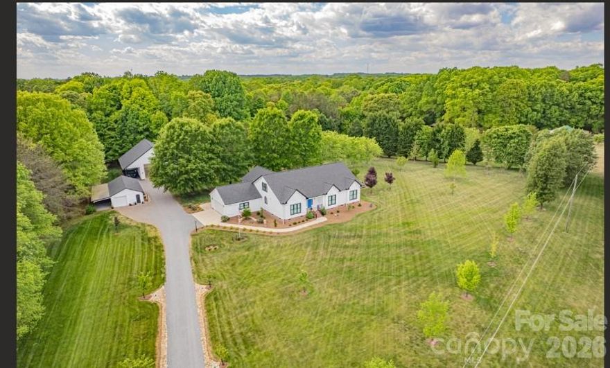 Discover an exceptional, fully updated home on 6 private acres, quietly situated at the end of the road. Over 3,500 sq ft of heated living space has been thoughtfully reimagined for comfort, entertaining, and dream-sized hobbies. 9' ceilings, rich solid wood details, a remodeled kitchen with Cambria quartz counters and custom window treatments set a refined tone. The main floor features an open living room, a cozy sitting room and a formal dining area — all arranged to capture the views throughout the primary living space.

The master suite is a private retreat with a walk-in closet and a spa-like bath boasting a step-in shower, soaking tub and dual vanities. All baths are updated with cultured marble and quartz counters. An upstairs bonus room provides flexible space for family, guests or a home office.

Outdoor living is effortless on the covered, screened 20x26 porch with a built-in outdoor kitchen — ideal for year-round gatherings. A large fenced backyard offers room for play and the potential to add a pool.

Outbuildings are true highlights: a detached garage designed by a former NASCAR team executive offers motorcoach-sized space and versatile bays for vehicles, projects and storage. The large detached garage includes a half bath and a finished bonus space upstairs. With 200 amps and 30/50 amp hook-ups on an above industry standard 6 inch concrete slab and ready to go with a permitted septic, this extra-large garage space is ready for it all!    An additional garage provides covered truck parking and workshop space.

This move-in ready estate blends refined interior updates with expansive lifestyle amenities and serene country privacy — a must-see to fully appreciate all the property has to offer.